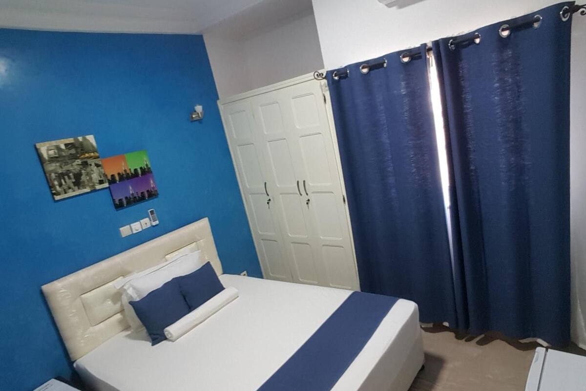 A bedroom with a bed, a nightstand, a wardrobe, and a curtain.