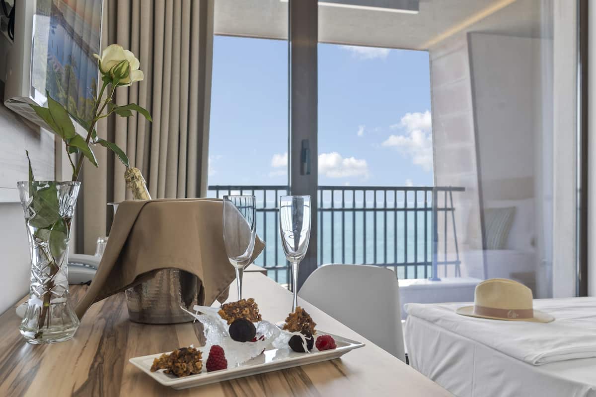 A dining table with a vase of flowers, a plate of desserts, and two champagne flutes.