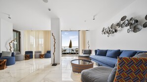 Een moderne woonkamer met een blauwe bank, een gestreept voetenbankje en uitzicht naar buiten.