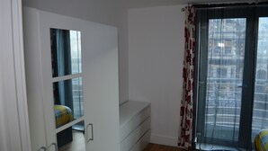 A room with a bed, a wardrobe, a window with curtains, and a door. - Executive Apartment Cardiff Central (Cardiff)