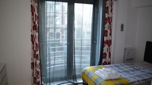 A hotel room with a bed, a window with curtains, a radiator, and a wall-mounted TV. - Executive Apartment Cardiff Central (Cardiff)