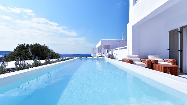 Un área de piscina moderna con vistas despejadas al mar, arquitectura blanca y mobiliario exterior.