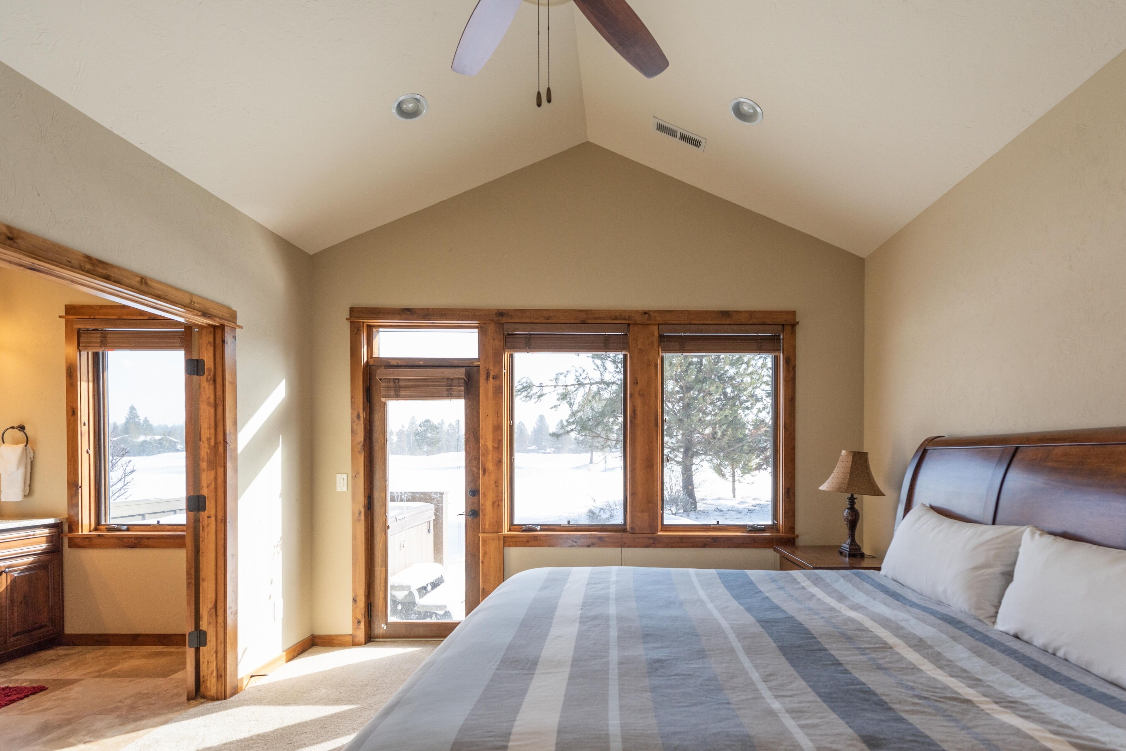 A bedroom with a large bed, wooden windows, and a ceiling fan.