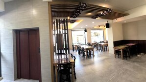 Een ruime restaurantruimte met meerdere tafels en stoelen, een houten scheiding en een plafond met bloemdecoraties.