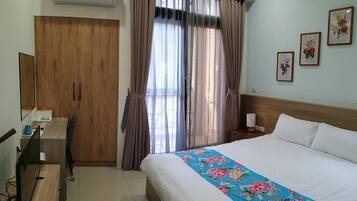Una habitación de hotel con cama, escritorio, aire acondicionado, armario y cortinas.