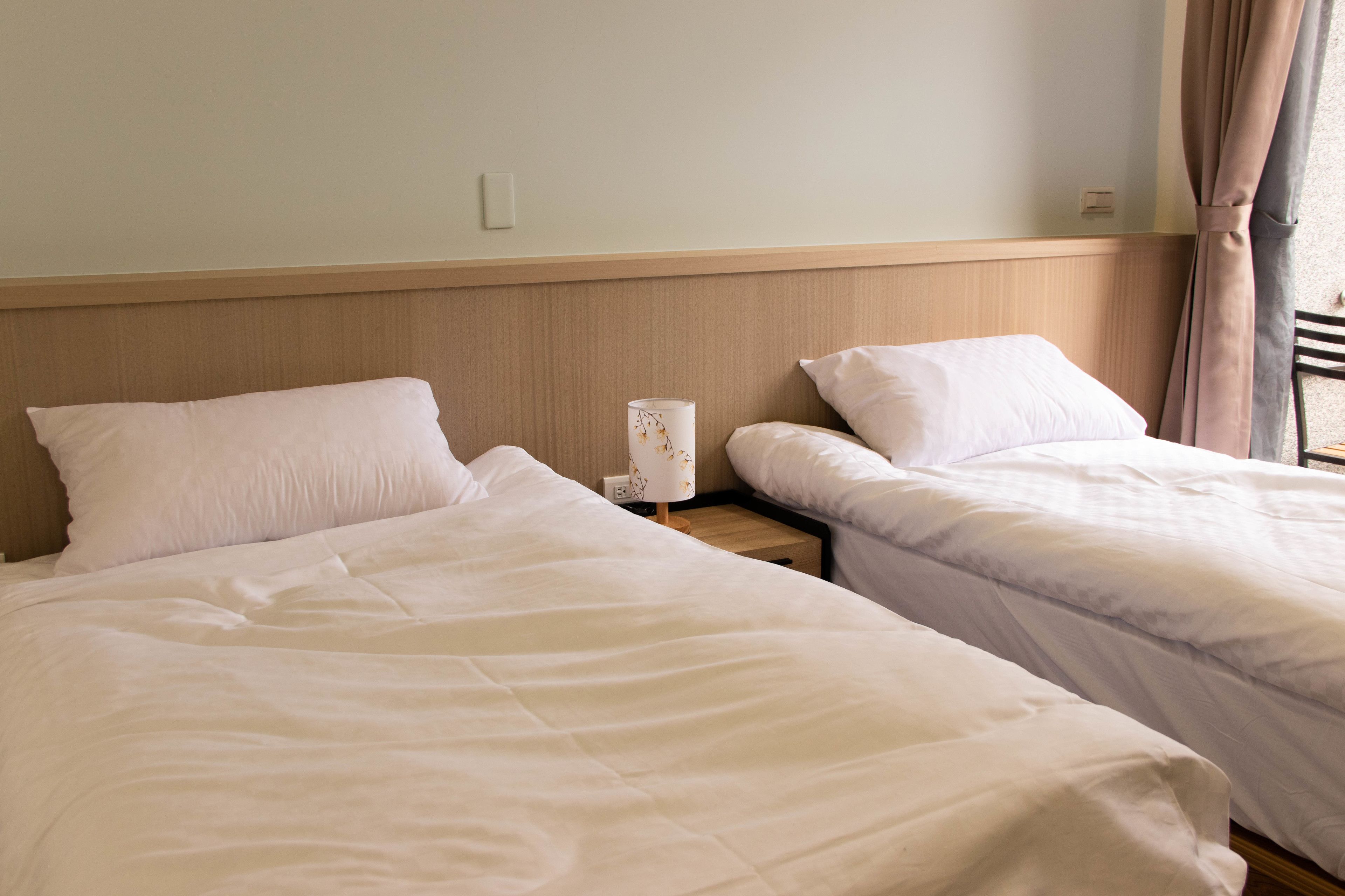 Twee enkele bedden met witte lakens in een hotelkamer.