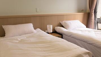 Twee enkele bedden met witte lakens in een hotelkamer.