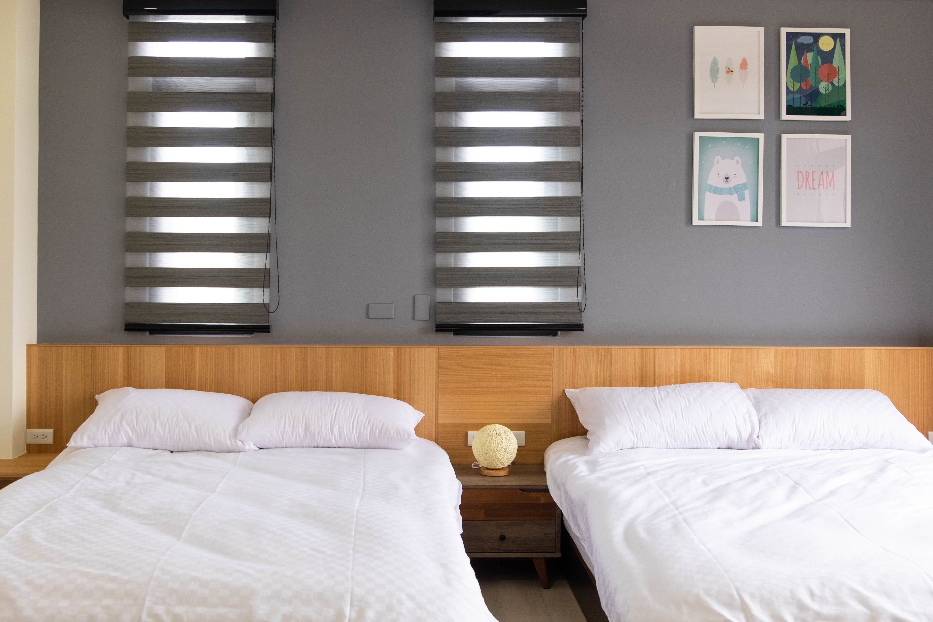 A bedroom with two beds, a wooden headboard, and a wall-mounted light fixture.