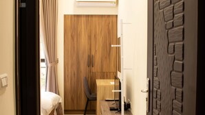 Een hotelkamer met een bed, bureau, stoel, lamp en kledingkast.