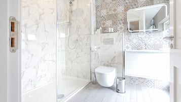 A modern bathroom with a glass-enclosed shower, a white toilet, and a sink with a mirror.