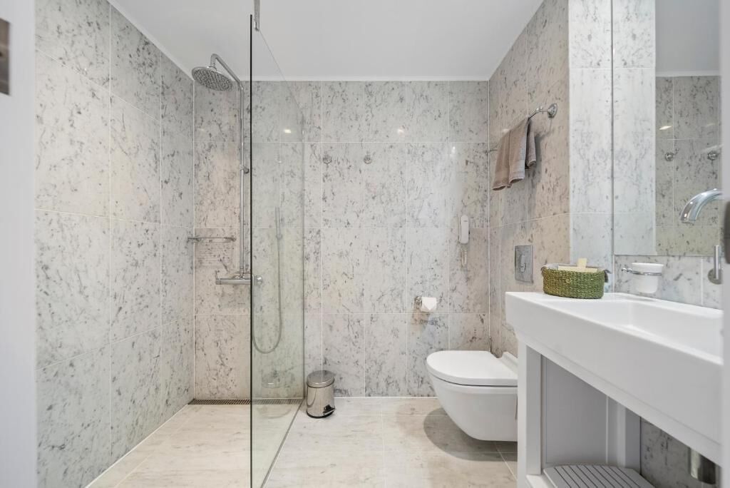 Une salle de bain moderne avec une douche à parois de verre, des toilettes et un lavabo avec un miroir.
