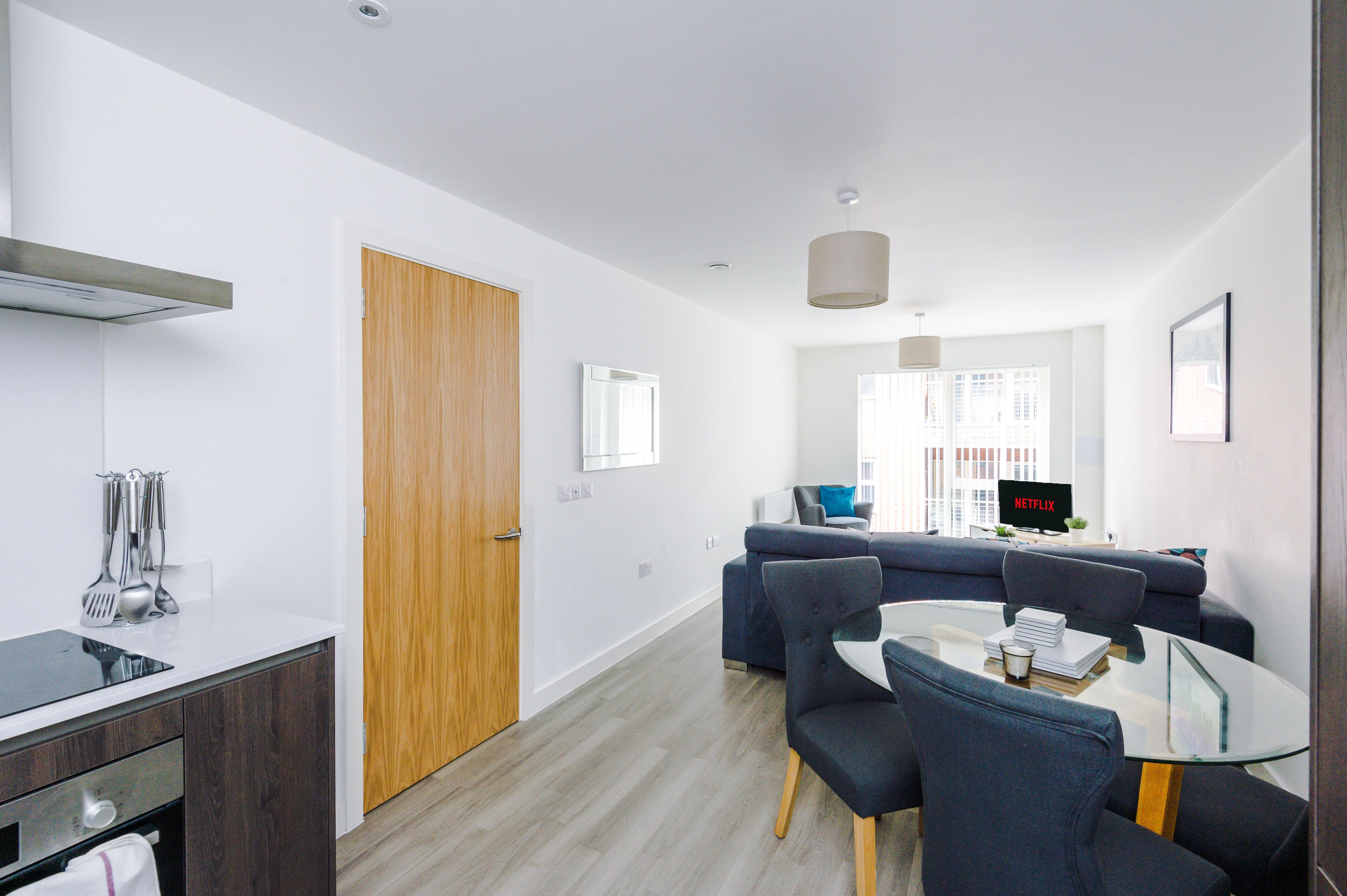 A modern living room with a sofa, a glass coffee table, and a television displaying 'NETFLIX'.