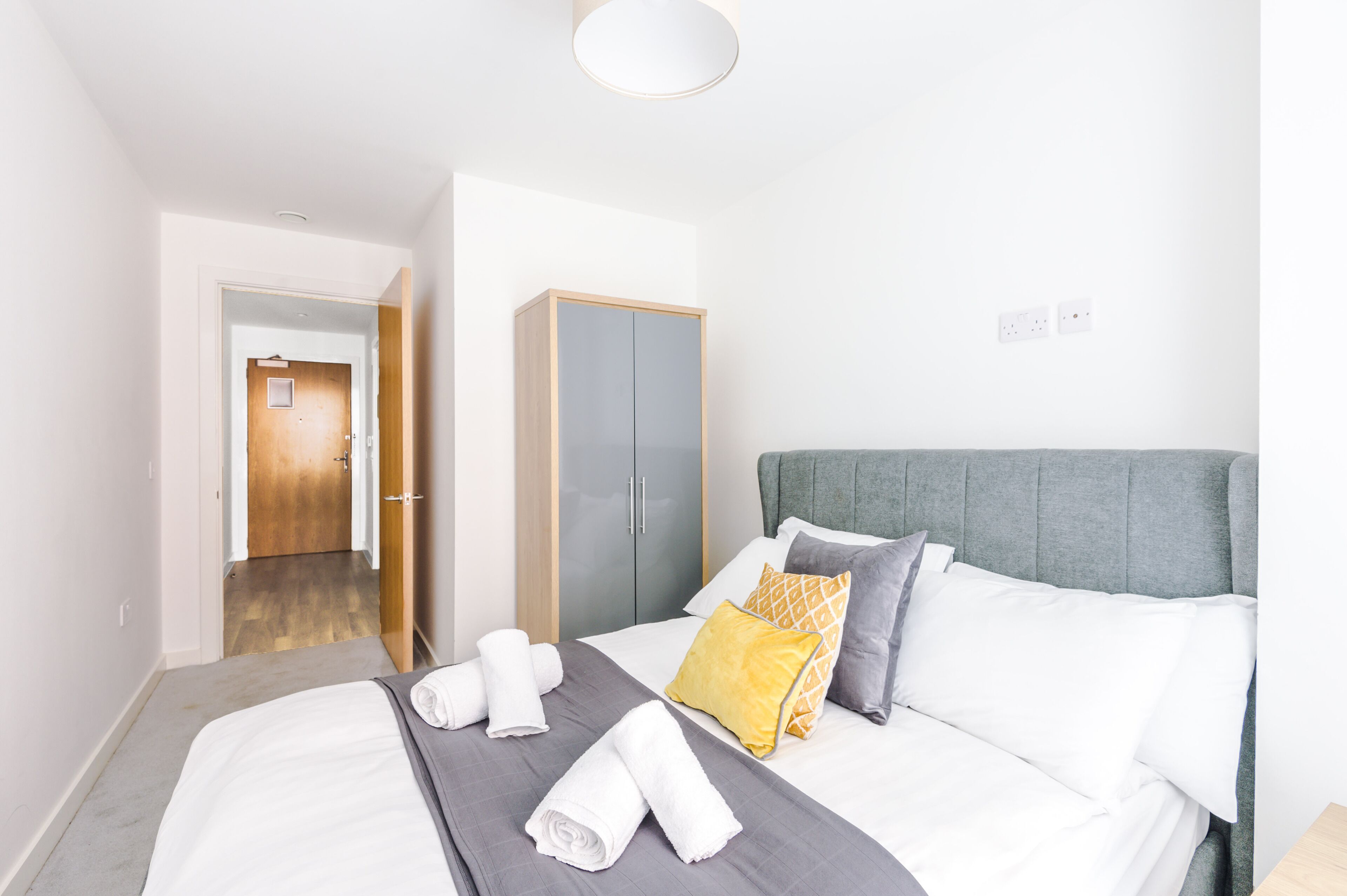 A hotel room with a bed, a wardrobe, and a door leading to another room.