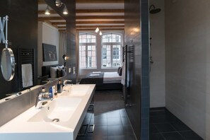 A modern bathroom with two sinks, a large mirror, and a shower. - Kerkstraat Residence (Amsterdam)
