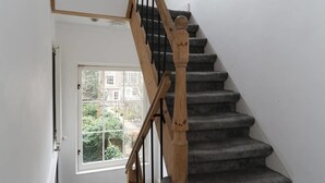 A staircase with wooden balusters and carpeted steps leading to a door with a window. - Kerkstraat Residence (Amsterdam)