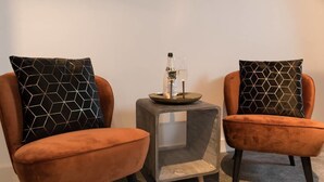 Two armchairs with geometric patterned cushions, a small side table with a bottle and glass, and a clear glass block base. - Kerkstraat Residence (Amsterdam)