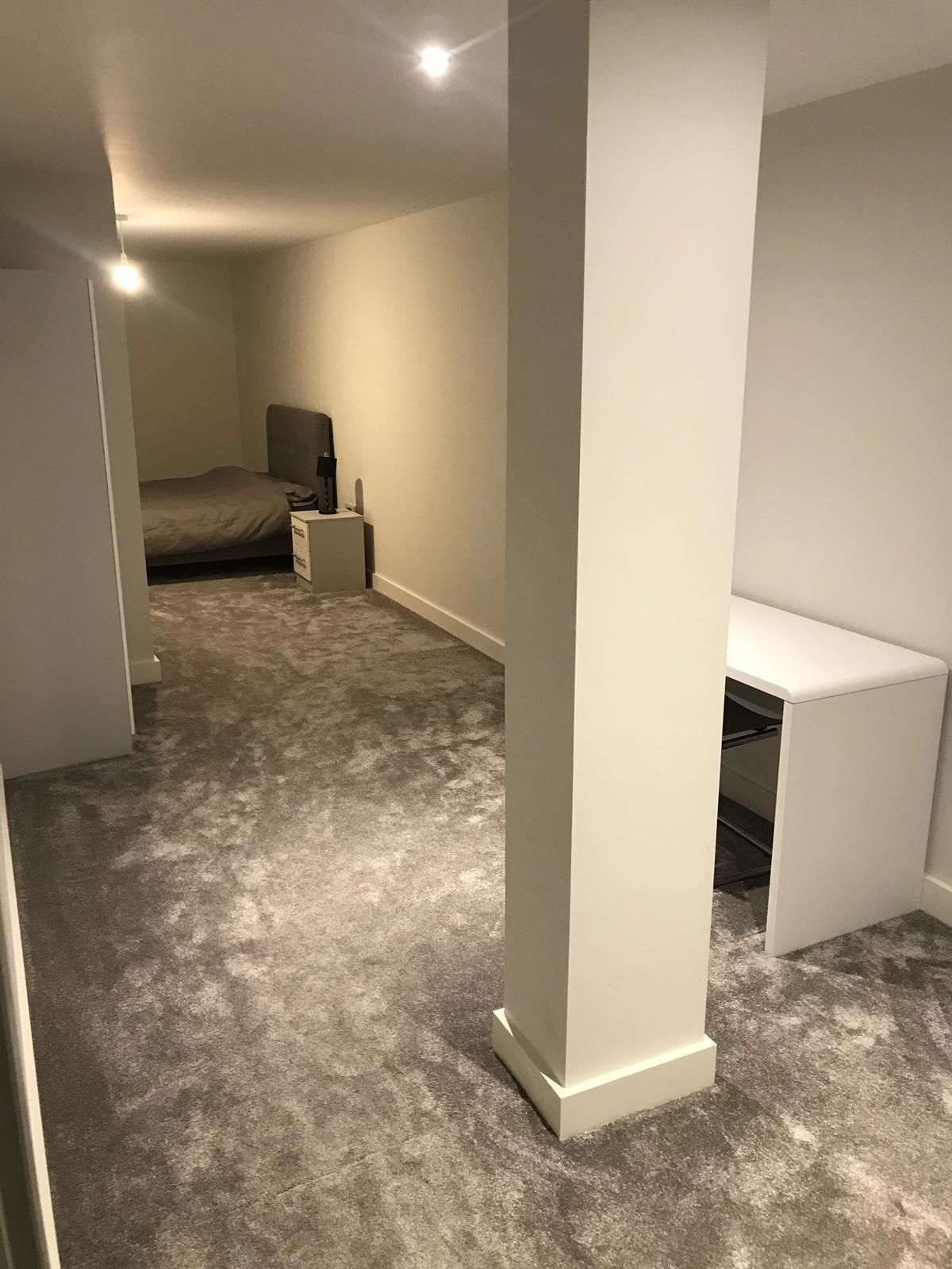 A bedroom with a bed, bedside table, and a desk.