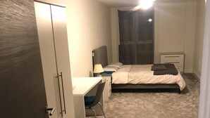 A bedroom with a bed, a desk, a chair, and a wardrobe. - 2 Bedroom Luxury Apartment in Leicester (Leicester)