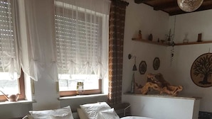 Une chambre à coucher avec un lit en bois, une literie blanche, une table de chevet, une lampe et une fenêtre avec des rideaux.