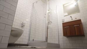 A bathroom with white subway tiles, a glass-enclosed shower, a wooden vanity, and a white sink. - Marnix residence (Amsterdam)