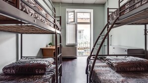 A dormitory room with bunk beds, a radiator, a window, and a small table. - Mister Econom Hotel - Hostel (Lviv)