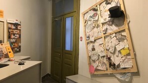 A reception area with a bulletin board displaying various notes and a clock on the wall. - Mister Econom Hotel - Hostel (Lviv)