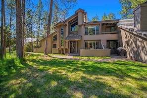 A modern two-story house with a large front porch, a covered entryway, and a spacious backyard.