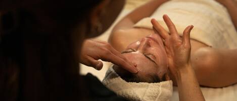 A person lying down with hands raised, possibly receiving a massage.