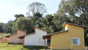 Tres casas de una sola planta con antenas parabólicas, rodeadas de vegetación y árboles.