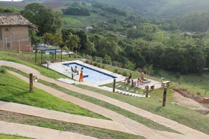 Una piscina con cubierta de madera, rodeada de césped y árboles.