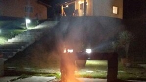 Hoguera al aire libre de noche con llama visible, rodeada por una estructura de concreto.