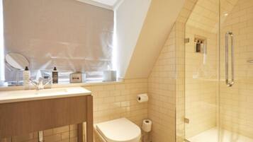 A bathroom with a shower, toilet, and sink with toiletries.