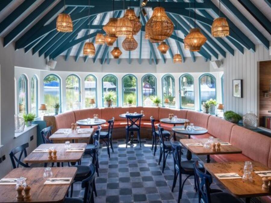 Un restaurante con suelo a cuadros, mesas de madera y una zona central con un banco acolchado.
