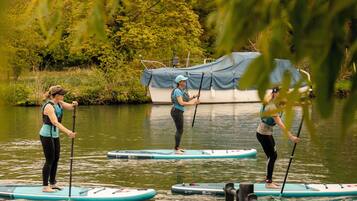 Three people paddleboarding on a calm river with trees in the background.