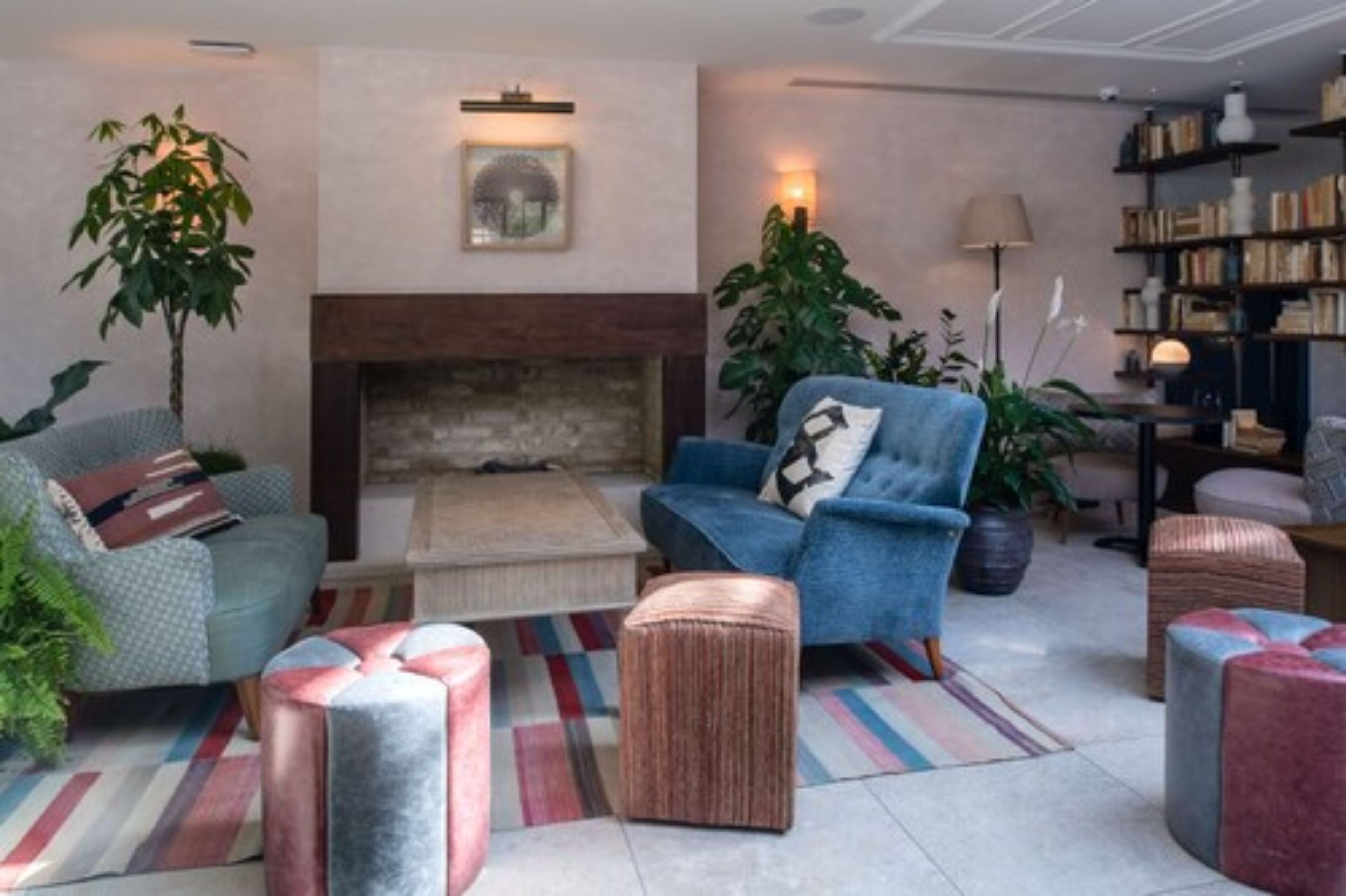 Una sala de estar con chimenea, un sofá, una silla y una estantería.