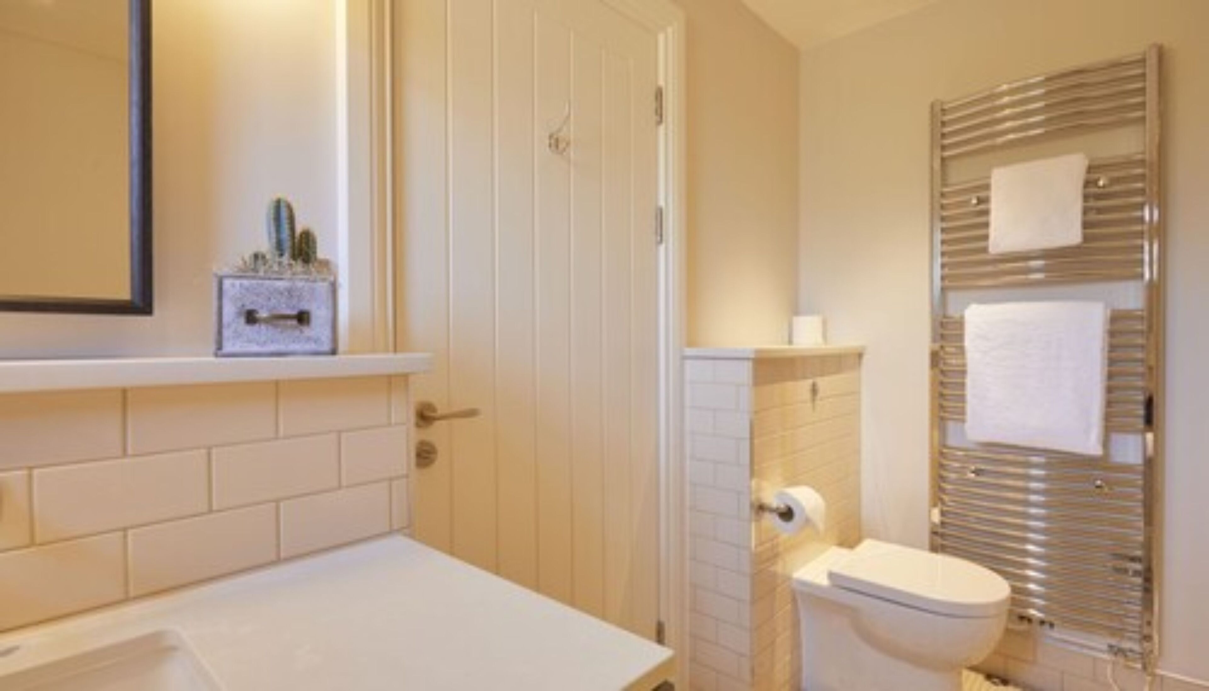 A bathroom with a white bathtub, a toilet, and a towel rack with two towels.