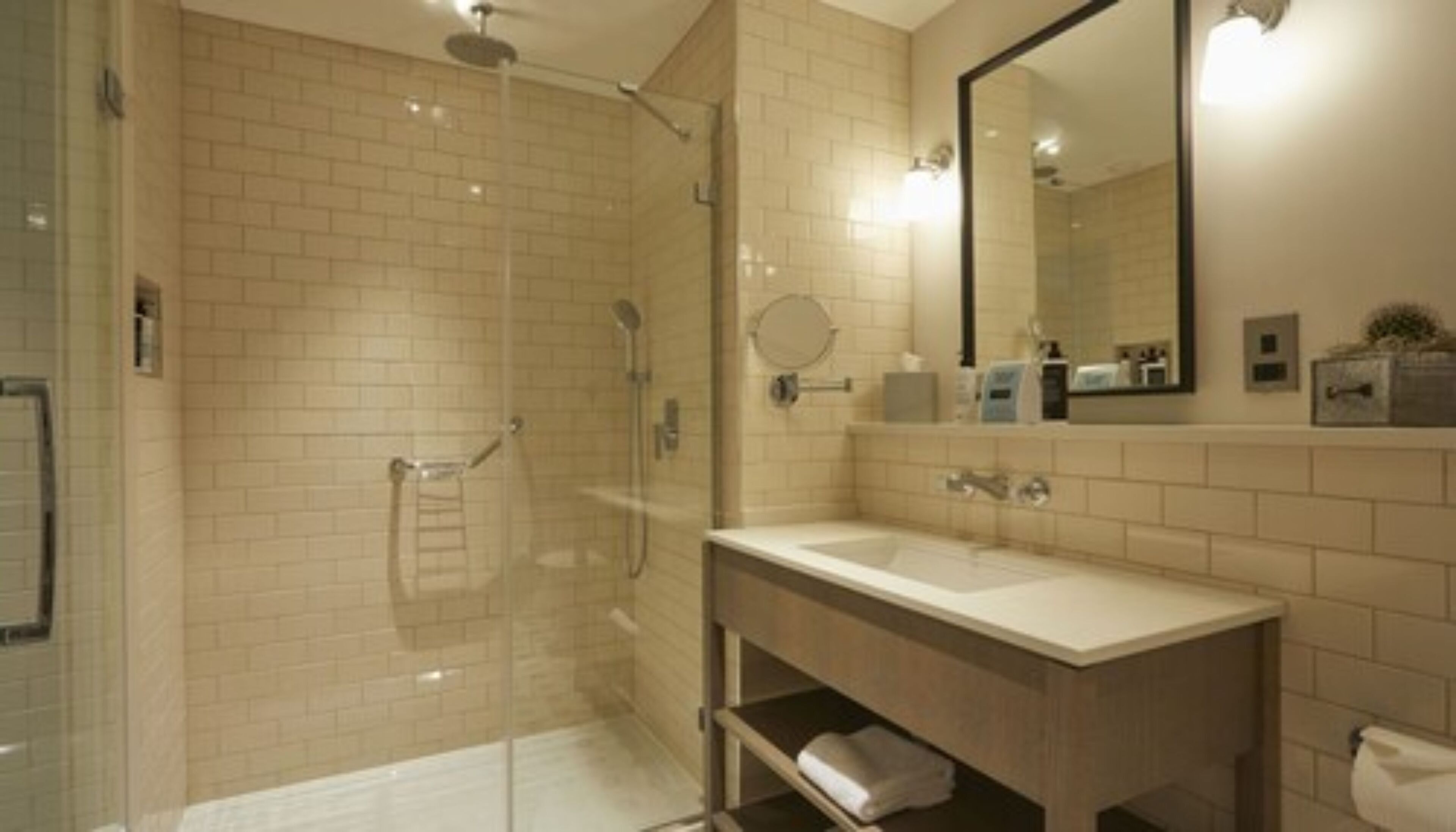 Un baño moderno con ducha de vidrio, tocador con espejo y un inodoro.