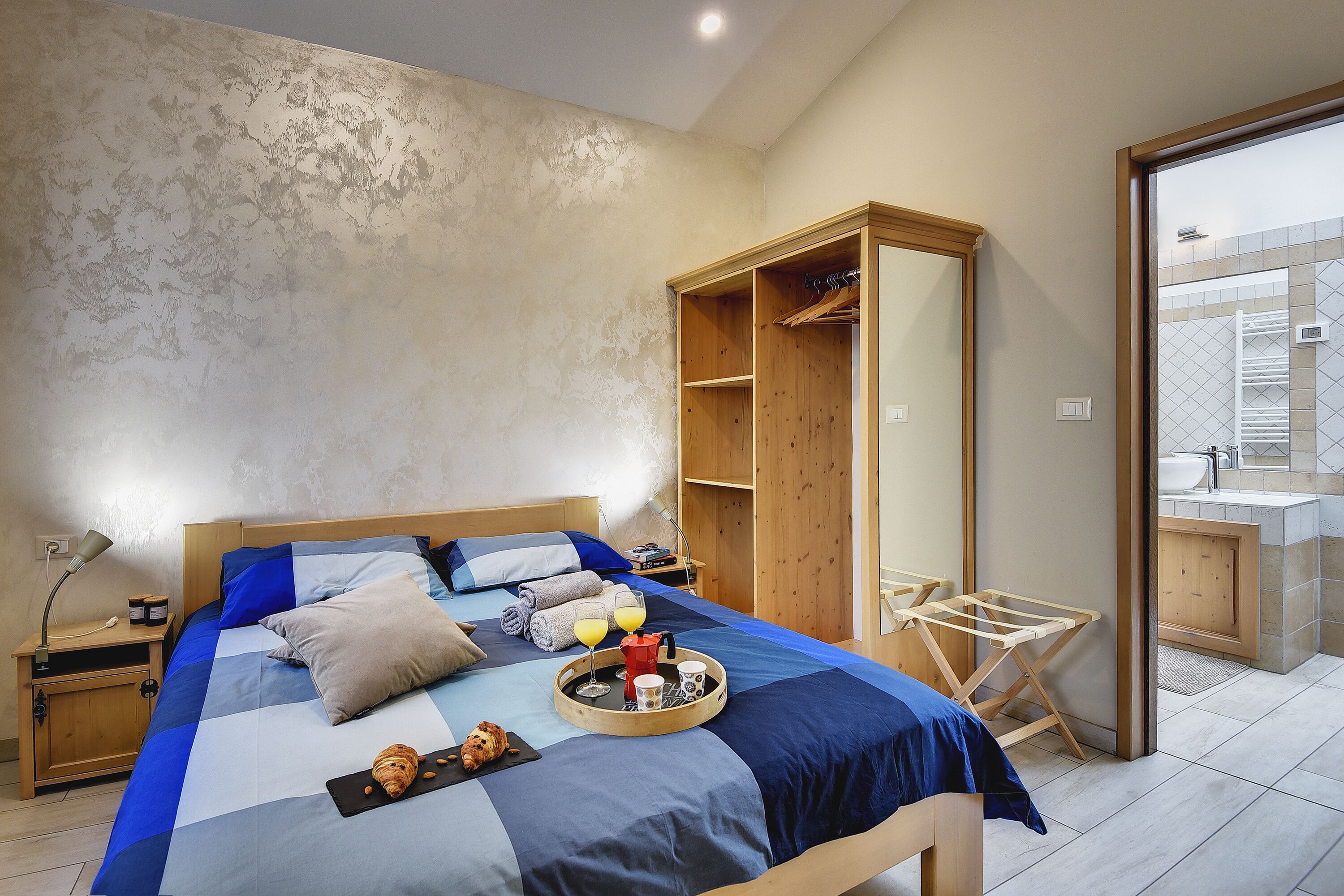 A bedroom with a bed, bedside table, and a wooden wardrobe.