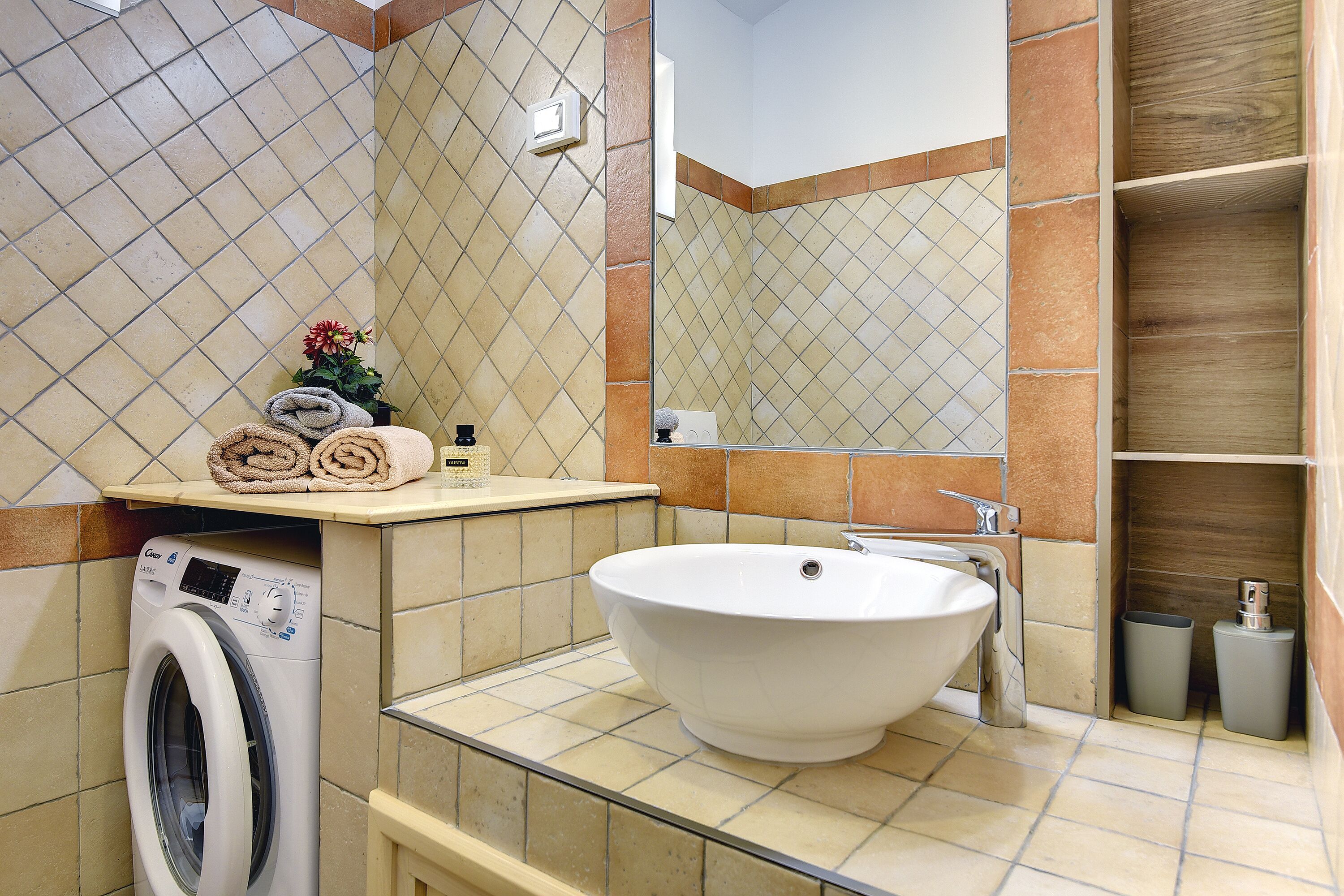 Un baño con lavadora, lavamanos y espejo.