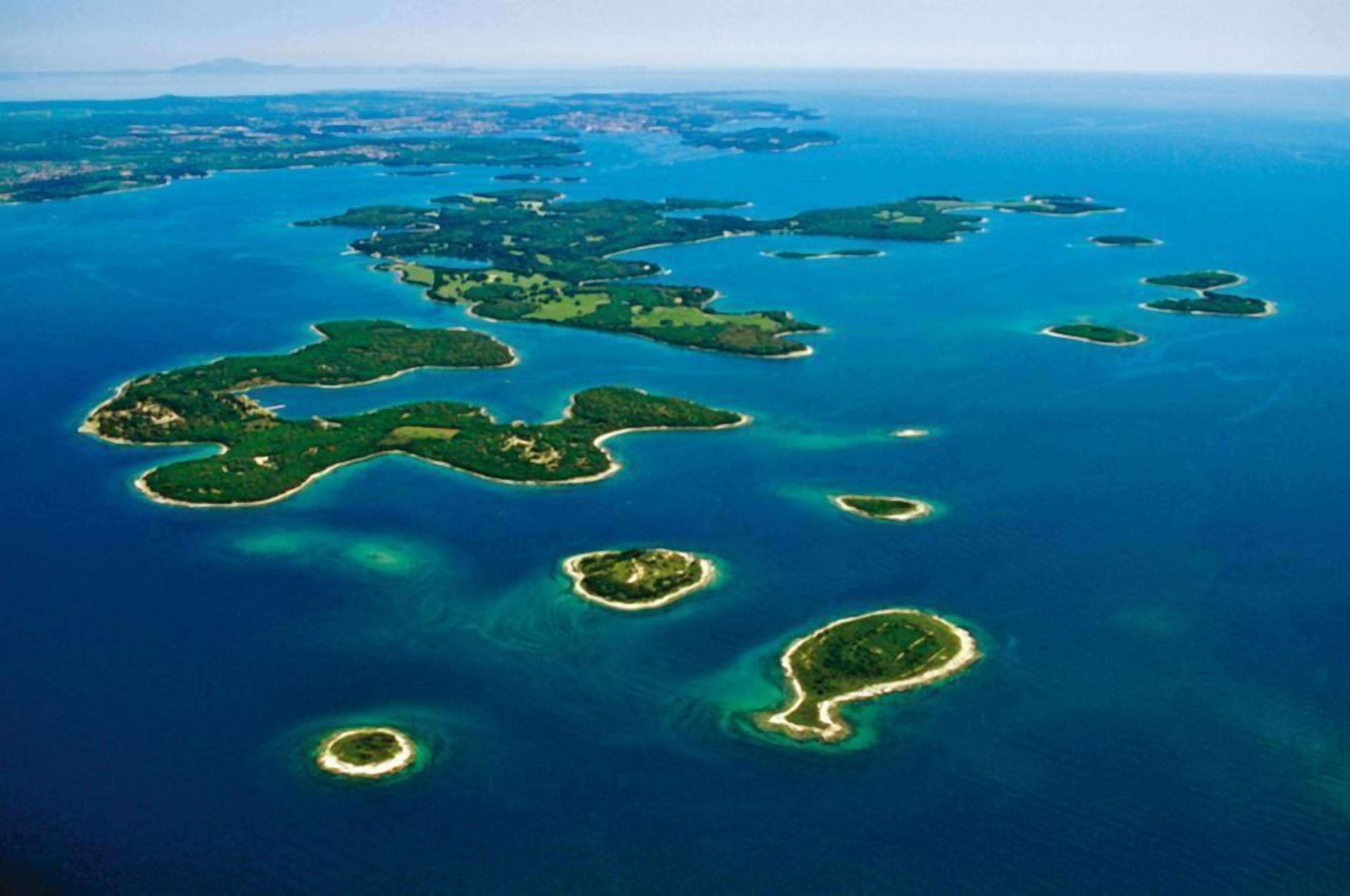 An aerial view of a chain of islands with clear blue waters and lush green vegetation.