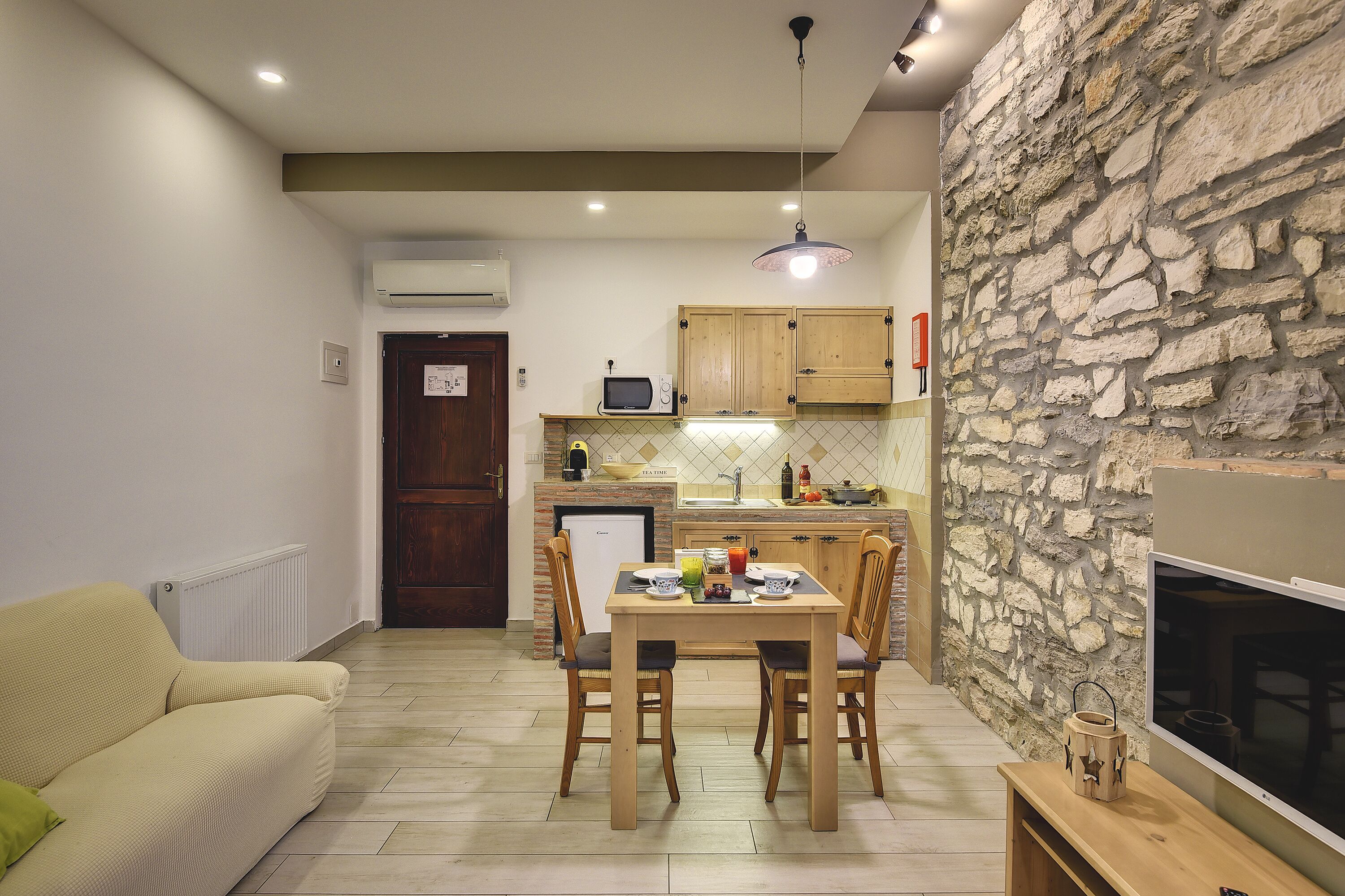 Un espacio habitable compacto con comedor, kitchenette y una pared de acento de piedra.