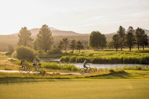 A golf course with a river, trees, and cyclists.