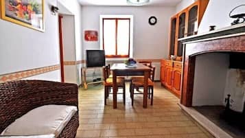 A compact living space with a dining table, chairs, a sofa, a television, and a fireplace.