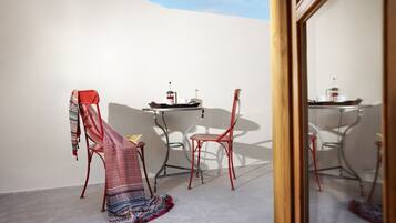 A room with a red chair, a small table with a coffee pot, and a patterned rug.