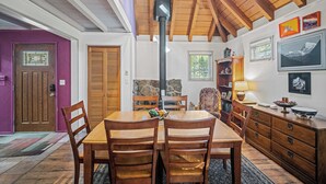 Un coin repas avec une table et des chaises en bois, un mur en pierre et une cheminée.