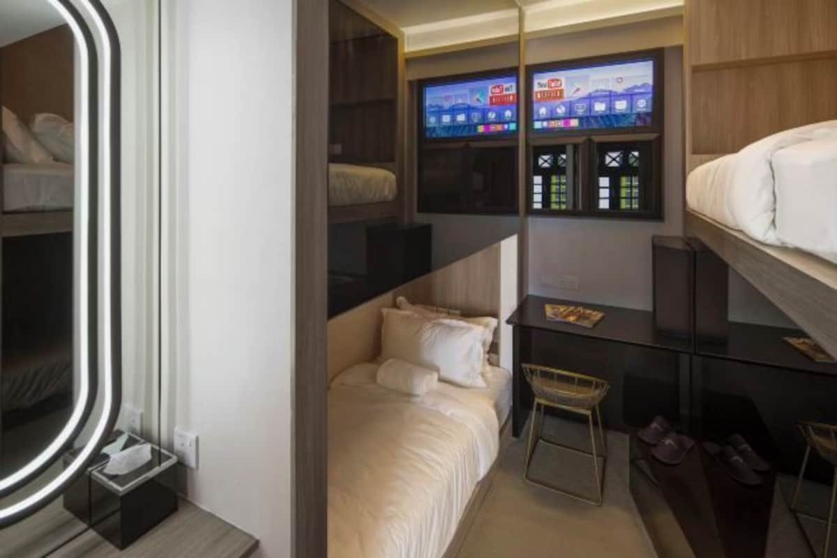 A modern hotel room with a bed, a TV mounted on the wall, and a shoe rack.