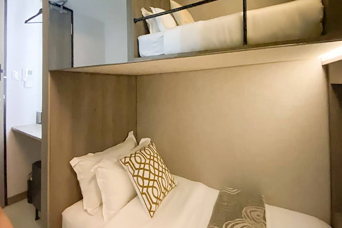 A bunk bed with a mirror above the lower bunk and a patterned pillow on the lower bed.