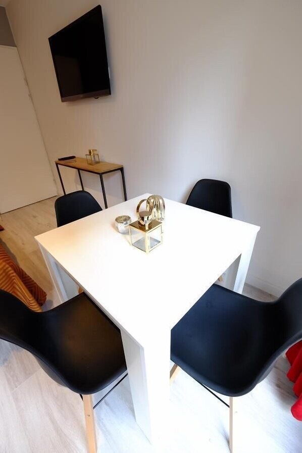 A modern dining area with a white table, black chairs, and a small side table with a decorative item. - City Centre Residence (Amsterdam)
