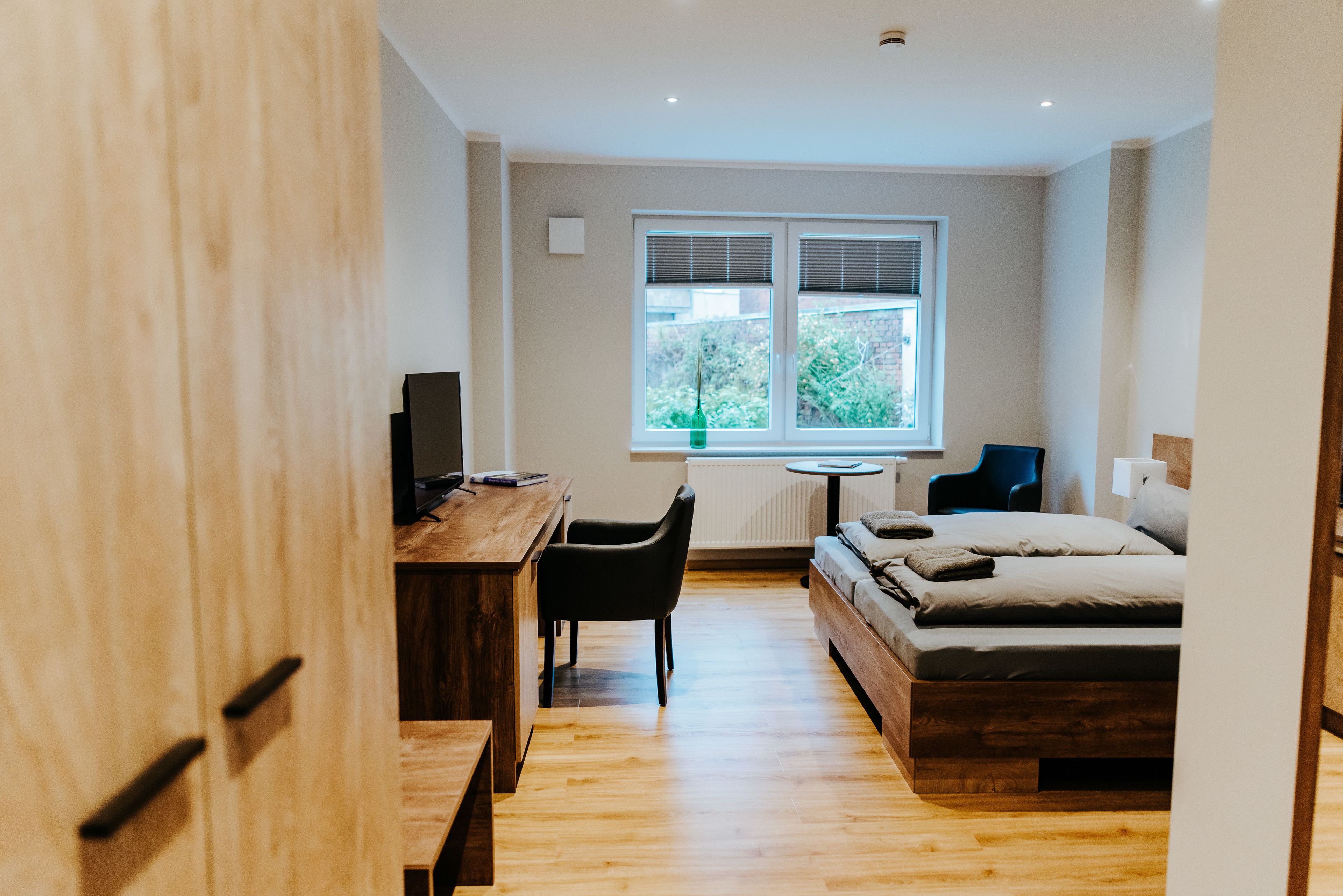 Ein modernes Schlafzimmer mit einem Holzbett, einem Schreibtisch und einem Stuhl.