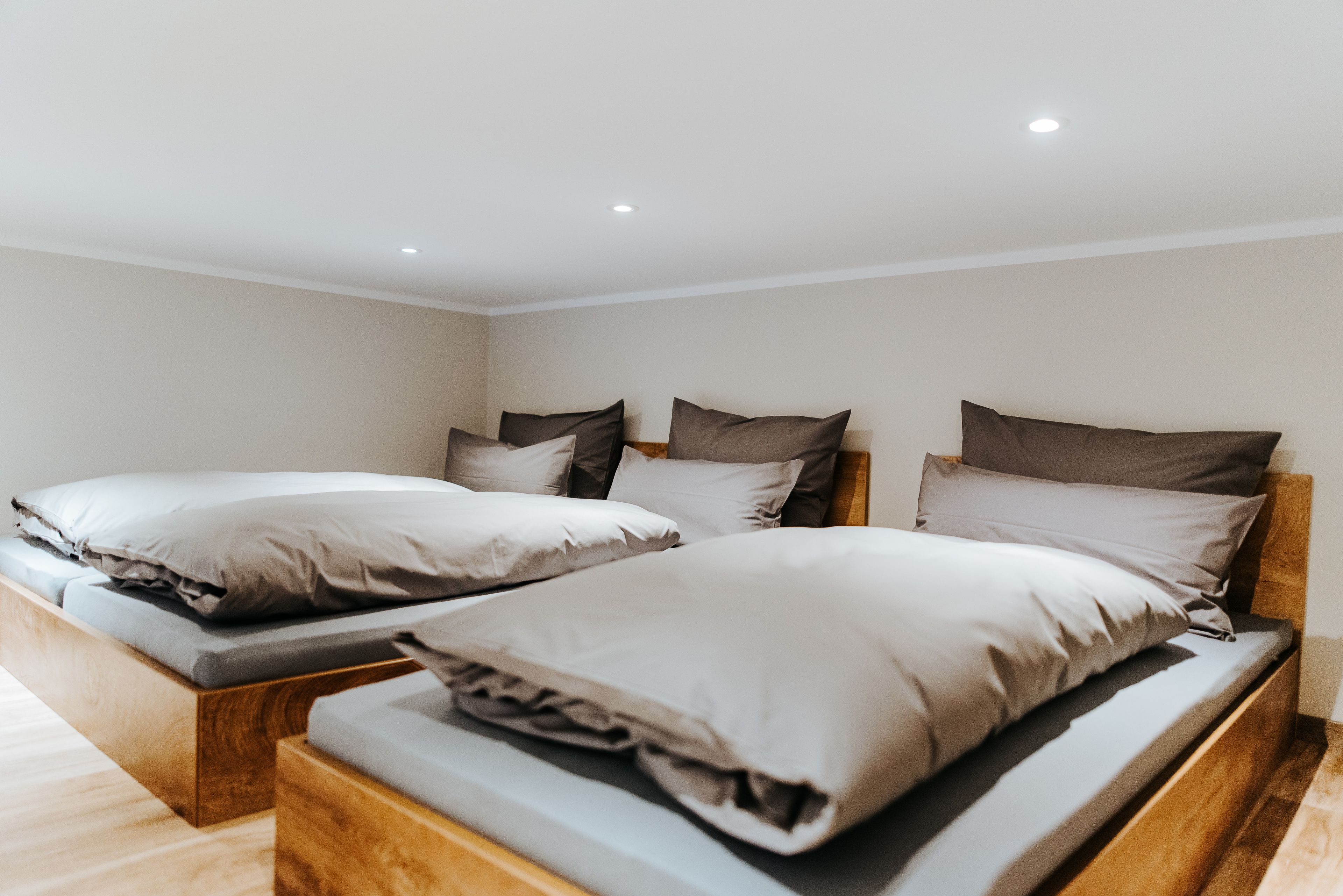 A bedroom with two beds, each with a wooden headboard and multiple pillows.